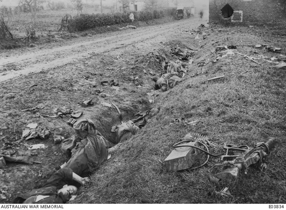 Australian War Memorial archival photo of German dead in a rudimentary roadside trench at Montbrehain.